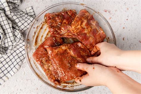 Fotografía de costillas de cerdo marinando en un recipiente hermético