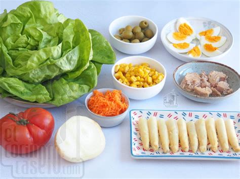 Ingredientes frescos para ensalada de pasta: lechuga, tomates, huevos, queso, aceitunas, espirales crudos.