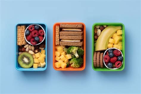 Fotografía de una lonchera escolar balanceada con bastones de verduras y fruta fresca.