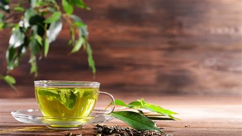 Taza de té verde con rodajas de jengibre fresco y hojas de té