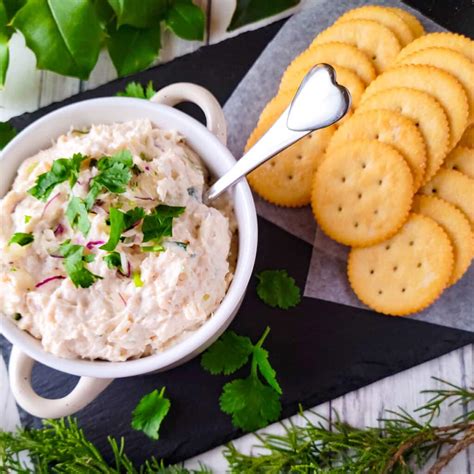 Fotografía profesional de un dip de pollo cremoso servido en un cuenco con tostadas y vegetales frescos para untar.