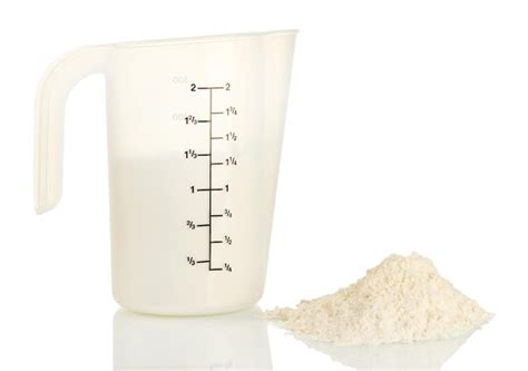 Fotografía técnica de una taza medidora siendo nivelada con un cuchillo para una medición precisa de harina