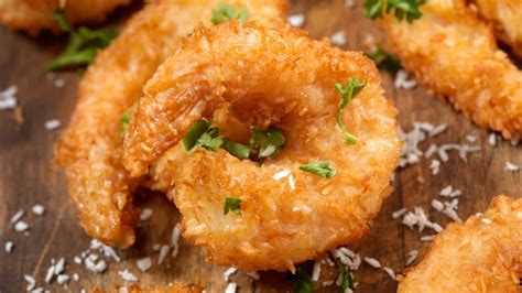 Camarones con coco rebozados servidos como aperitivo, con una bebida tropical al lado.
