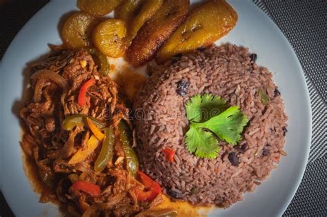 Imagen de un plato cubano con cerdo en salsa, arroz congris, tostones y ensalada