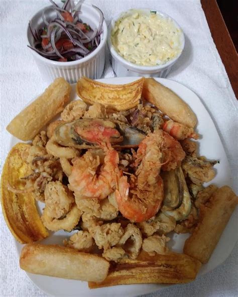 Plato de Jalea Mixta, con mariscos fritos crujientes, yucas fritas y sarza criolla, presentado de forma apetitosa.