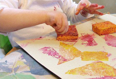 Niño estampando con una hoja y pintura sobre papel.