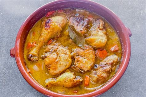 Cazuela de barro con piezas de pollo, papas y una salsa de adobo espesa y brillante