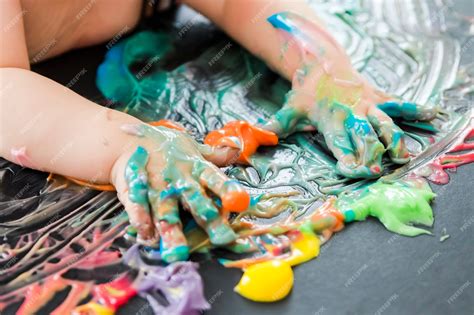 Foto de bebés pintando con sus manos usando pinturas de colores brillantes en una bandeja.