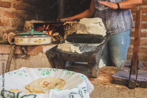 Mujer indígena mixteca haciendo tortillas a mano en un metate y comal de barro.