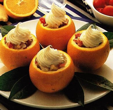 Fotografía cenital de naranjas vaciadas y rellenas con crema, decoradas con trozos de chocolate y pistachos.