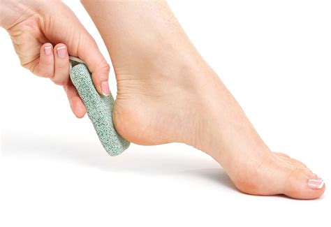 Mujer usando piedra pómez para exfoliar sus pies.