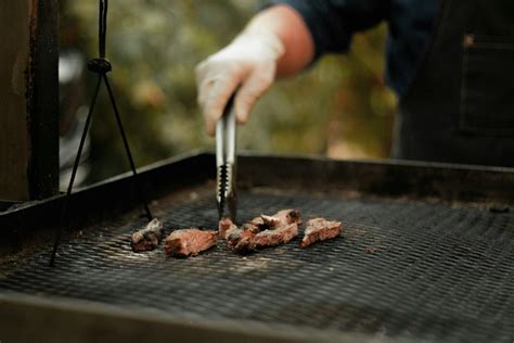 Chef asando carne en una parrilla de carbón al aire libre