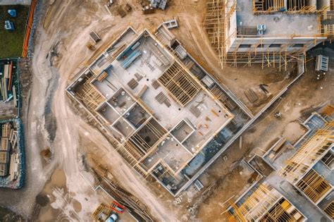Vista aérea de un sitio de construcción moderno en Los Ángeles con maquinaria pesada y materiales de construcción apilados.