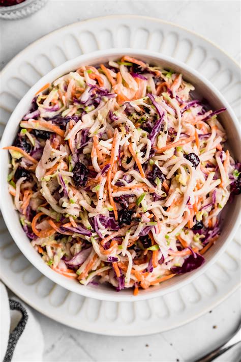 Un bol de ensalada coleslaw con repollo morado y verde, zanahoria y trozos de manzana.