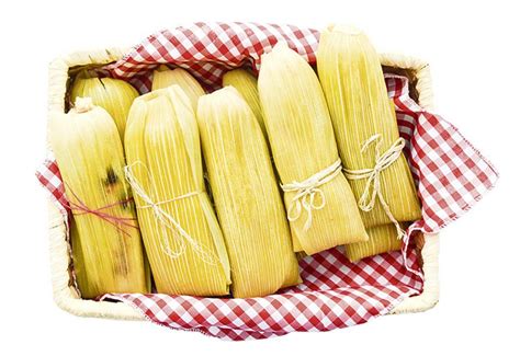 Fotografía detallada de tamales bolivianos envueltos en chalas de maíz listos para la cocción al vapor.