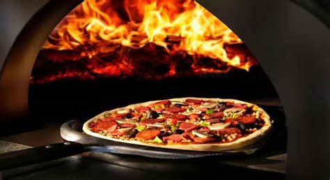 Pizza horneándose en un horno de piedra, con el borde dorado y el queso burbujeando