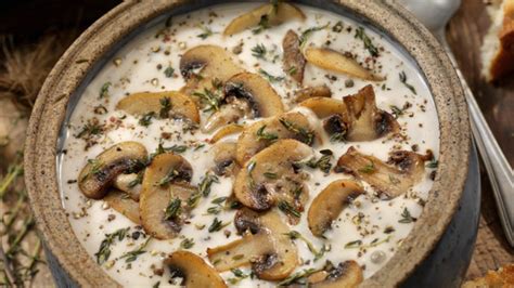 Plato de champiñones con crema agria servido sobre una base de puré de patatas con hierbas frescas