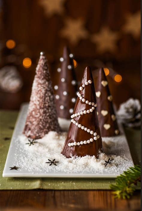 Fotografía detallada de arbolitos de chocolate sobre palitos decorados con perlas de azúcar