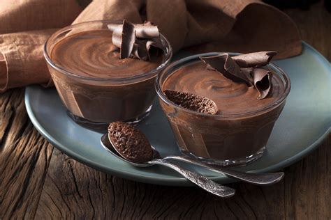 Fotografía profesional de una mousse de chocolate servida en copa con frutos rojos frescos y una textura aireada.