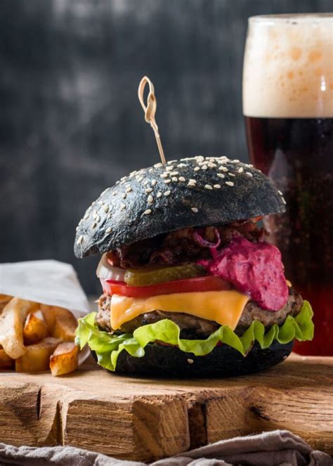 Foto de hamburguesa con pan negro decorada con queso en forma de dientes y salsa roja