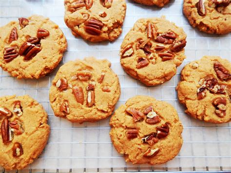 Imagen de galletas de nuez delgaditas, doradas y bien presentadas sobre una bandeja de madera.
