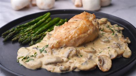 Plato de pechuga de pollo servido con una salsa cremosa y una guarnición elegante.