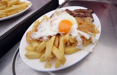 Fotografía gastronómica de un plato de Bistec a lo Pobre servido con su huevo, cebolla y papas fritas