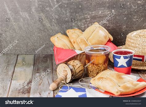 Fotografía de una mesa festiva chilena con empanadas de pino, chicha y adornos tradicionales.