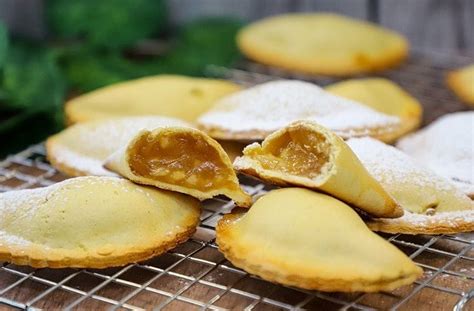 Fotografía detallada de empanadas de alcayota horneadas con un espolvoreado de azúcar flor.