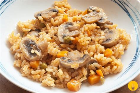 Plato de arroz salteado con champiñones dorados, huevo y tiras de tocino crujiente servido en un tazón