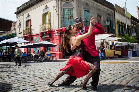 Fotografía de una pareja bailando tango en un escenario tradicional de Buenos Aires con mesas dispuestas para cenar.