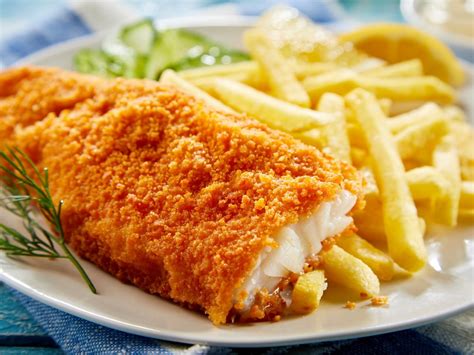 Plato de pescado frito con patatas fritas y ensalada en un restaurante costero