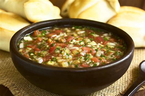 Composición visual con los ingredientes del pebre araucano y un bol con la salsa preparada.
