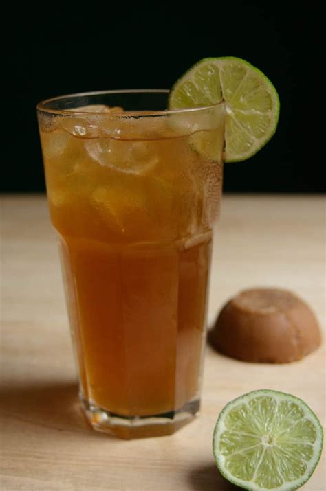Fotografía de un vaso de aguapanela fría con limón y hielo, y una taza de aguapanela caliente