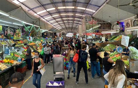 Fotografía de un mercado de abastos con comerciantes atendiendo a clientes