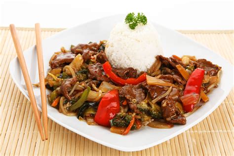 Plato servido de Chop Suey de carne con arroz blanco, decorado con sésamo y cebollín picado.