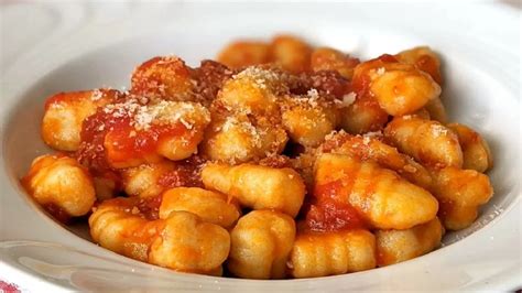 Fuente para horno con ñoquis de polenta cubiertos de salsa blanca y queso, listos para gratinar