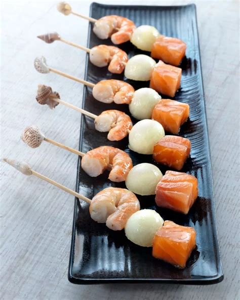 Brochetas de salmón ahumado, langostinos y melón presentadas en un plato