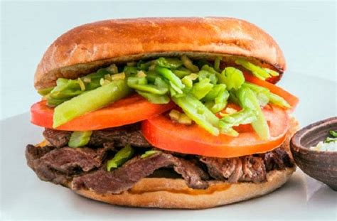 Infografía con los ingredientes principales del sándwich chacarero: carne, tomate, porotos verdes, ají y pan.