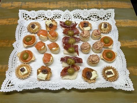 Fotografía de canapés variados servidos en tacitas comestibles, con énfasis en la frescura y el color de los rellenos.