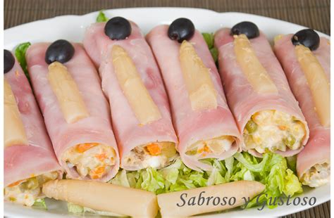 Plato terminado con rollitos de jamón rellenos de ensaladilla y ralladura de zanahoria decorativa.