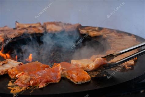 Chef volteando filetes de carne en una parrilla de horno caliente con pinzas