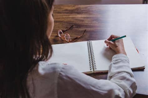 Foto de una persona escribiendo en un diario con una taza de té, simbolizando la reflexión y el manejo de emociones