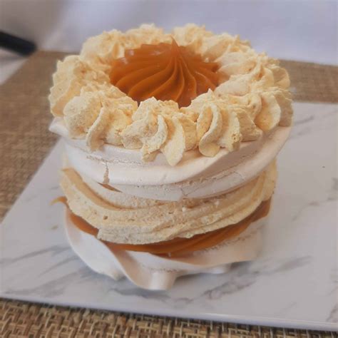 Infografía que muestra las capas de la torta de merengue lúcuma: discos de merengue crocante, crema chantilly de lúcuma y decoración final