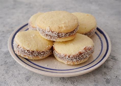 Foto detallada de alfajores de maicena terminados, con bordes cubiertos de coco rallado y una textura suave y desarmable.