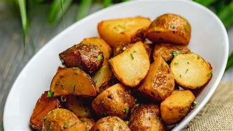 Fotografía profesional de un plato de papas asadas al ajo acompañadas de tiras de filete de res a la parrilla.