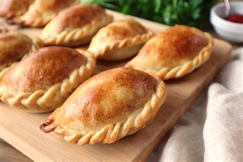 Fotografía gastronómica: una empanada artesanal de queso sobre un plato tradicional junto a una copa de vino.