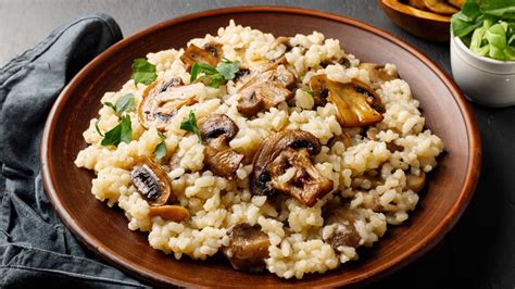 Un plato humeante de risotto de champiñones con una copa de vino tinto al lado.