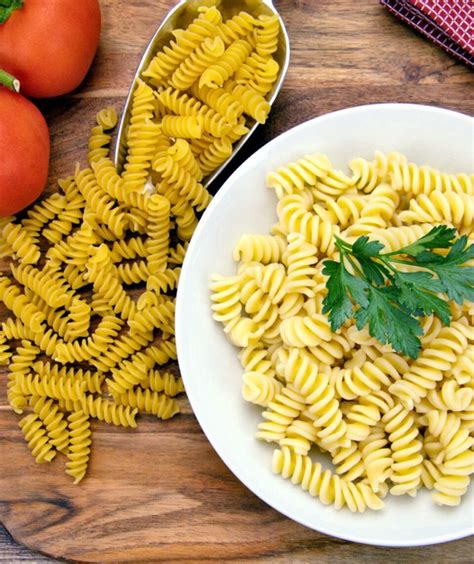 Un plato de pasta fusilli vibrante con trozos de pimiento rojo, aceitunas verdes y una cremosa salsa.