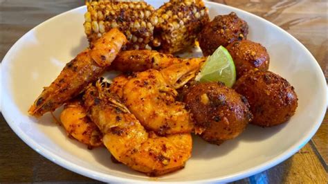 Arreglo de ingredientes frescos: camarones, papas, elotes, chorizo y especias.